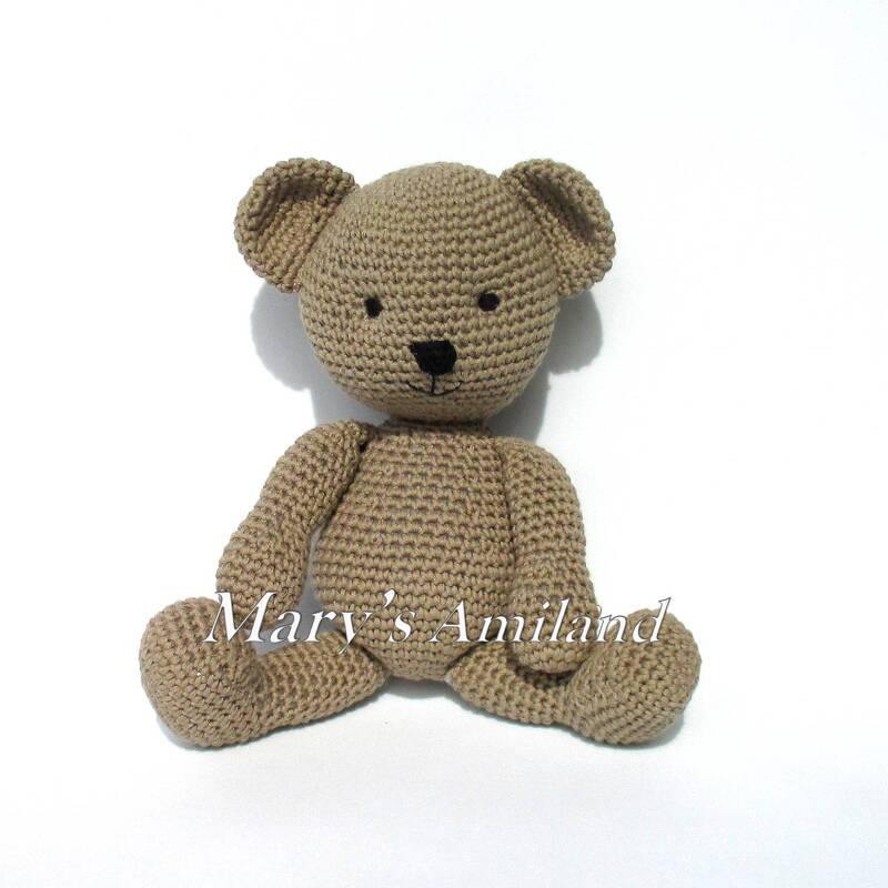 Beige crocheted amigurumi teddy bear sitting on white background
