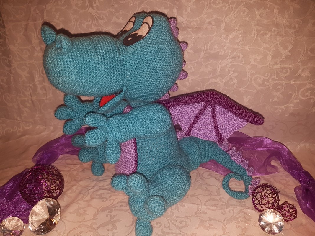 Sitzender gehäkelter Drache in Türkis und Violett, seitliche Perspektive