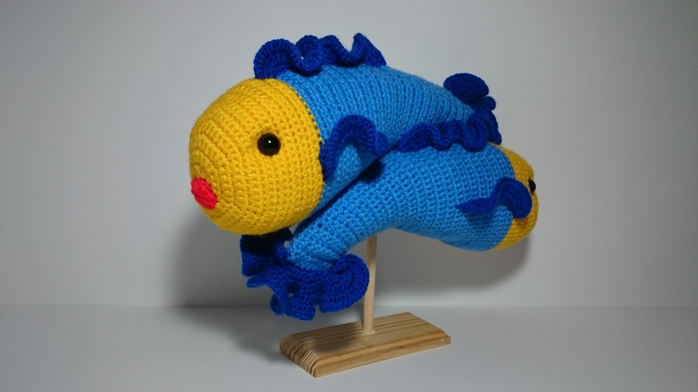 Gehäkelter Amigurumi-Fisch blau-gelb mit Rüschen auf Holzständer