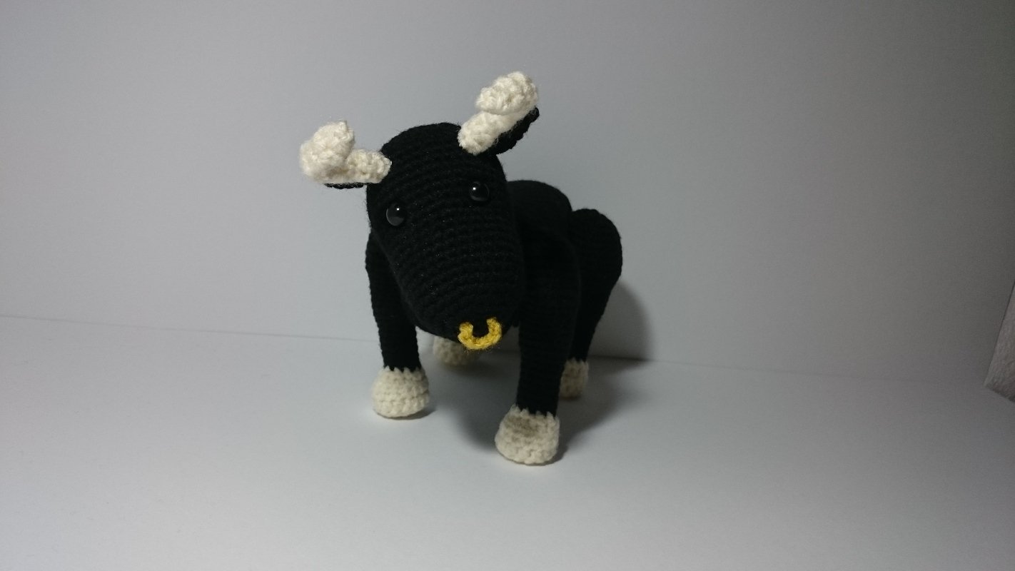 Gehäkelter schwarzer Stier mit cremefarbenen Hörnern und Hufen und gelbem Nasenring