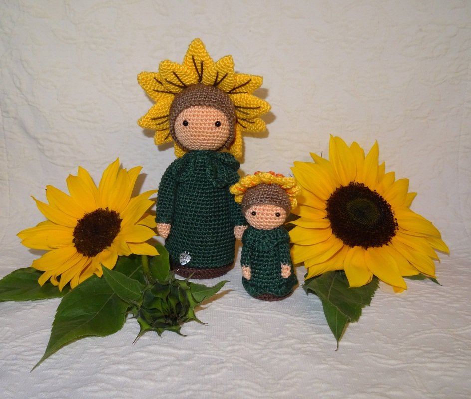 Große und kleine gehäkelte Sonnenblumen-Puppen nebeneinander mit Sonnenblumen