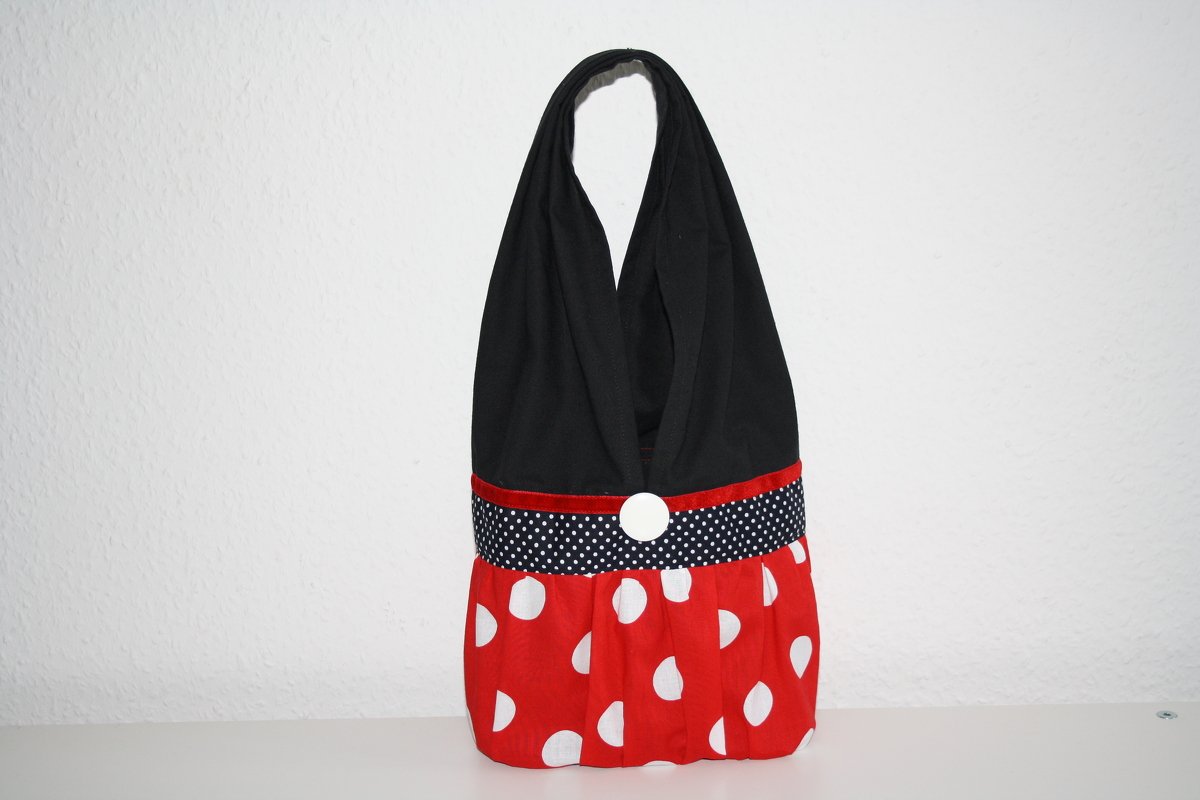 Stofftasche mit schwarzem Oberteil, gepunktetem Taillenband, rotem Unterteil und weißem Knopf