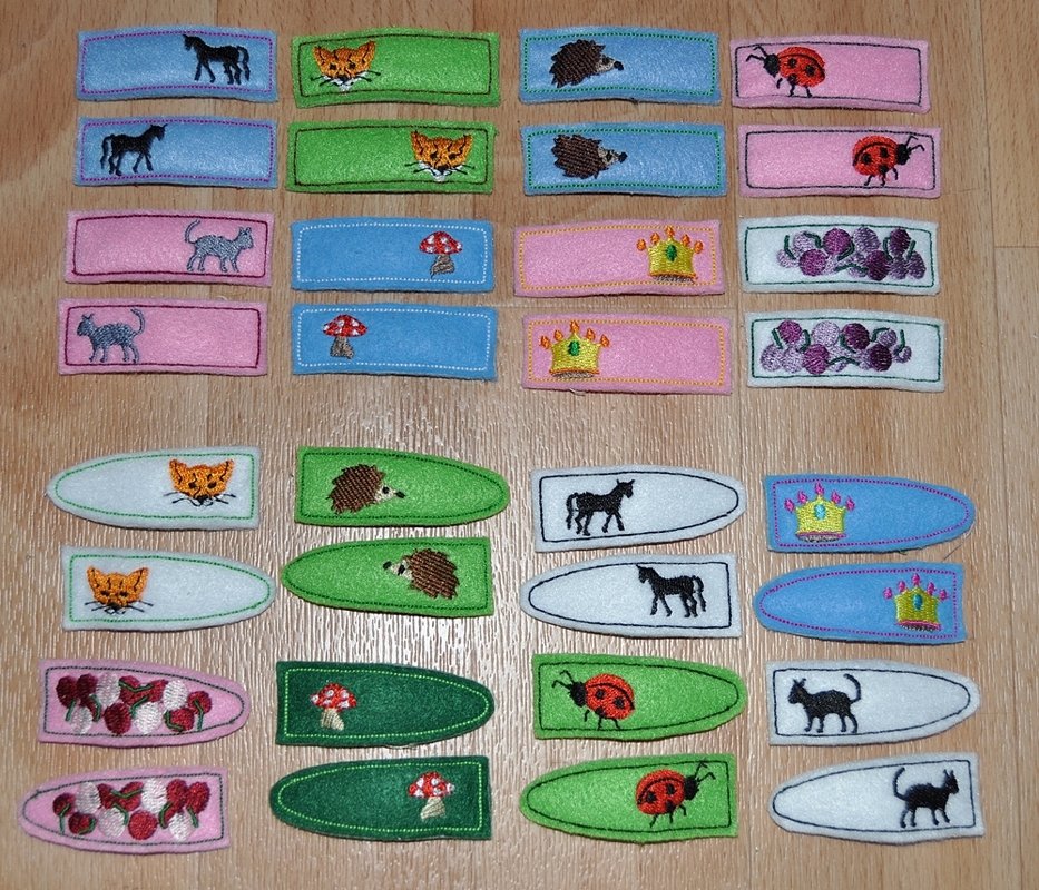 Viele ITH-Stickapplikationen mit Tieren, Pilzen, Kronen und Beeren auf Holzuntergrund.