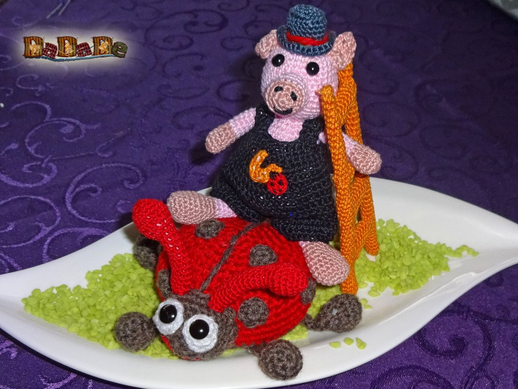 Festliche gehäkelte Deko: rosa Schweinchen mit Zylinder auf rotem Marienkäfer