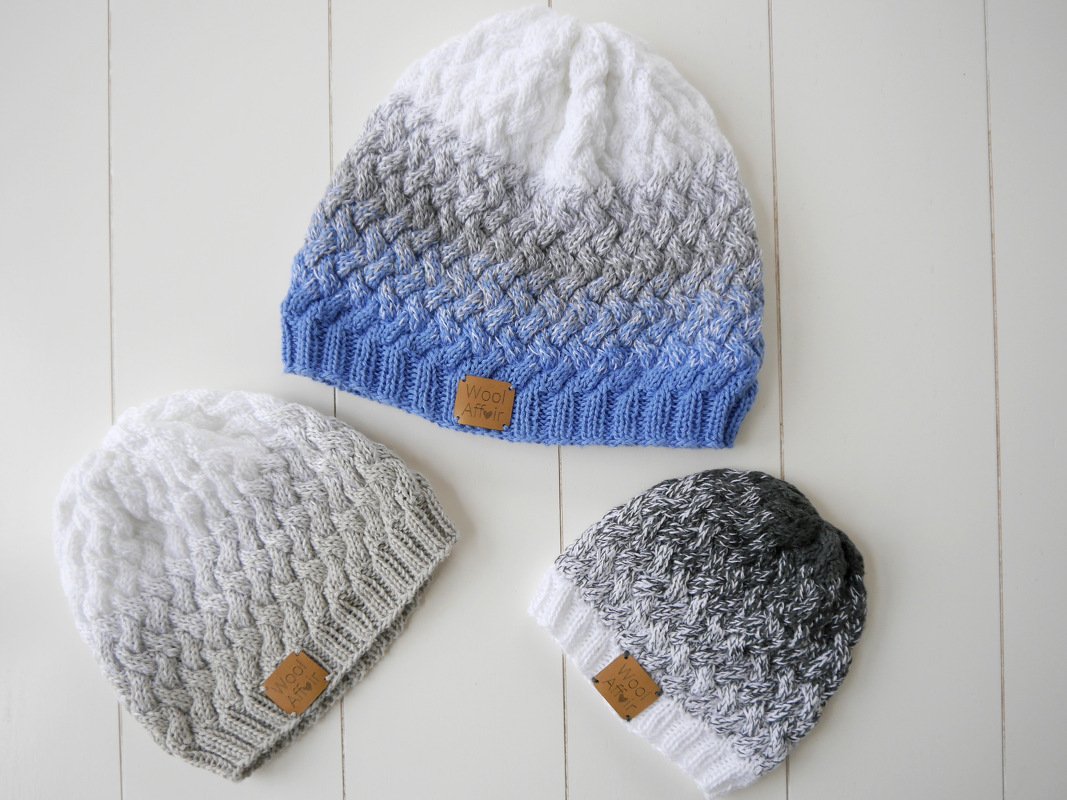 Drei gestrickte Mützen in Blau-, Grau- und Weißtönen mit Farbverlauf und Strukturmuster auf hellem Hintergrund