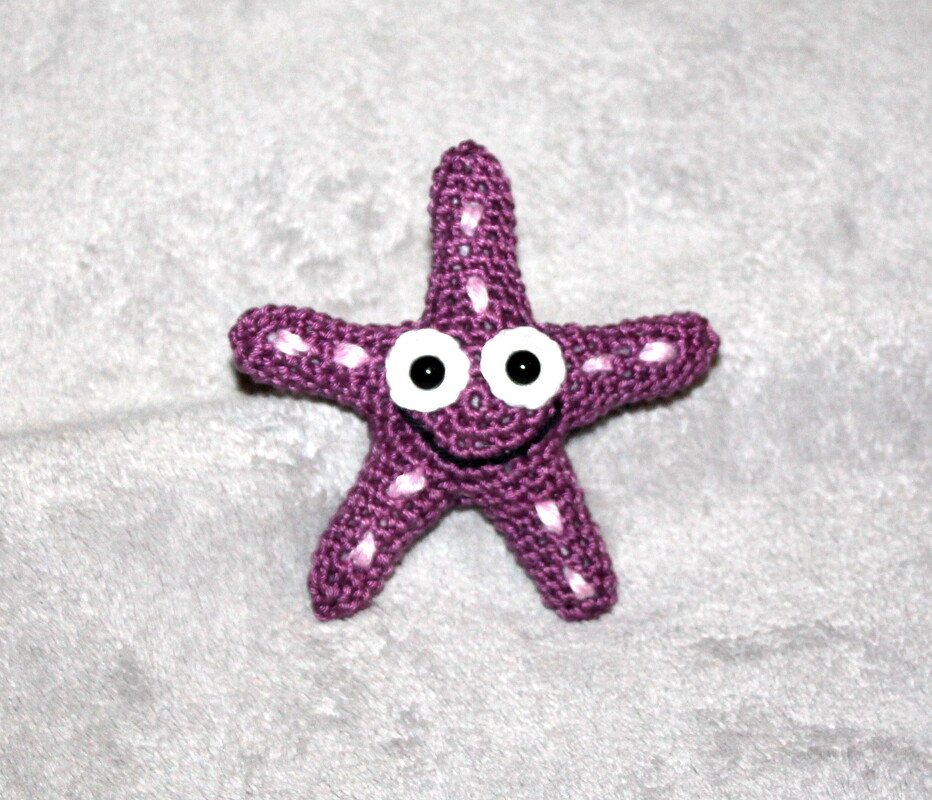 Fröhlich lächelnder lila Seestern aus Häkelgarn mit weißen Details