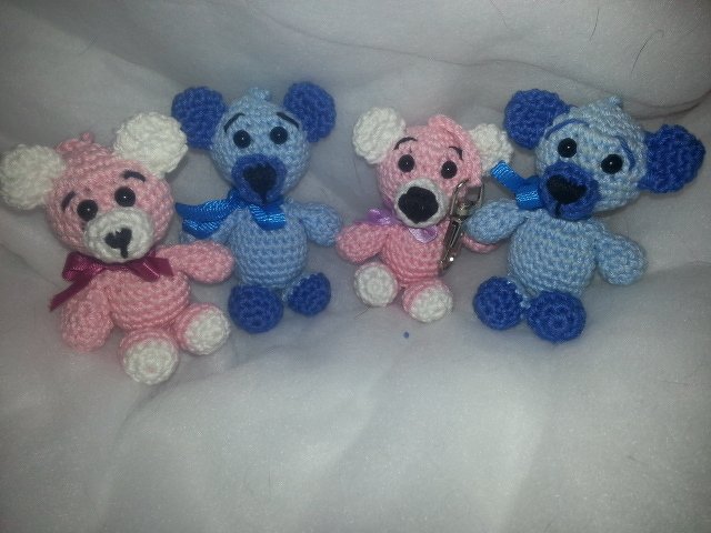Vier gehäkelte Amigurumi-Teddybären in Rosa und Blau, eines mit Schlüsselring.