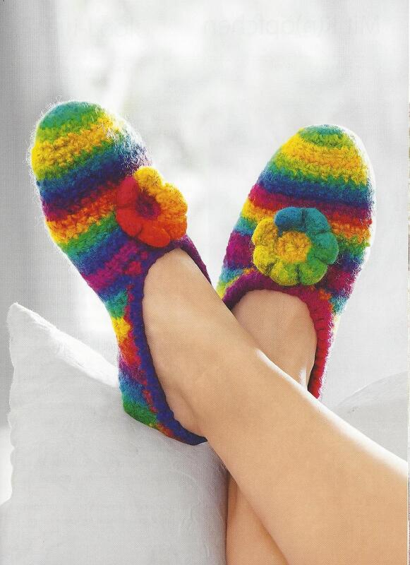 Nahaufnahme gehäkelter, gefilzter Puschen in Regenbogenstreifen mit Blütenapplikation