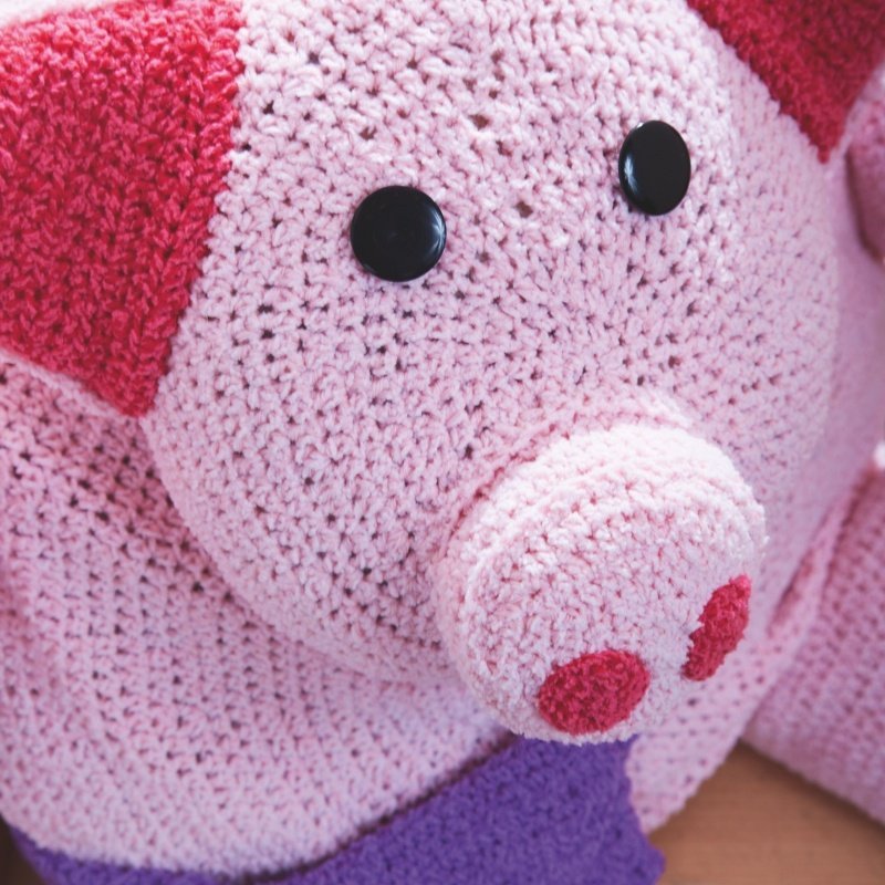 Rosa gehäkeltes Schweinekissen mit rundem Rüssel, schwarzen Knopfaugen und roten Ohren