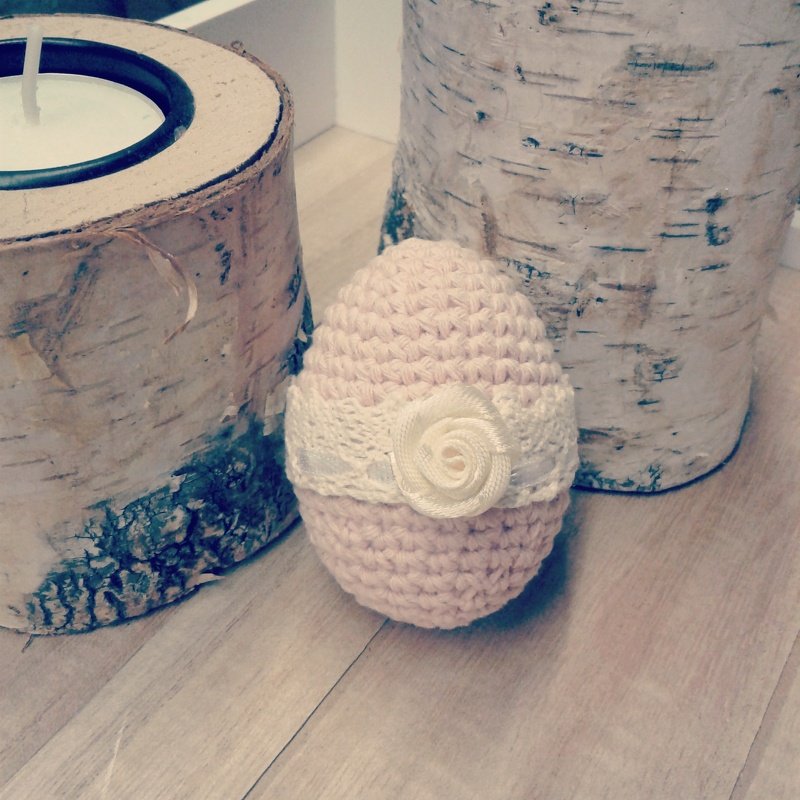 Rosa gehäkeltes Osterei mit weißem Spitzenband und Stoffrosen-Applikation vor Birkenholz-Deko