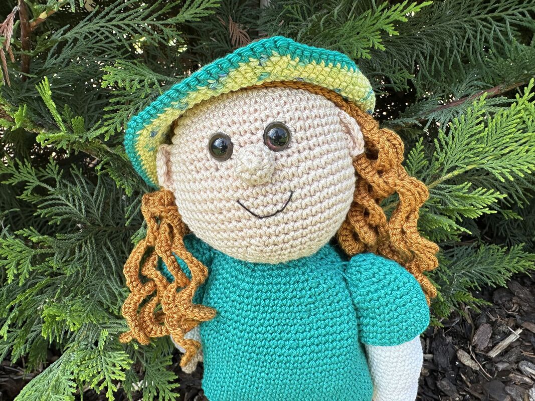 Gehäkelte Amigurumi-Puppe mit großem runden Kopf, Sicherheitsaugen, besticktem Lächeln, lockigen Haaren und gestreiftem Hut