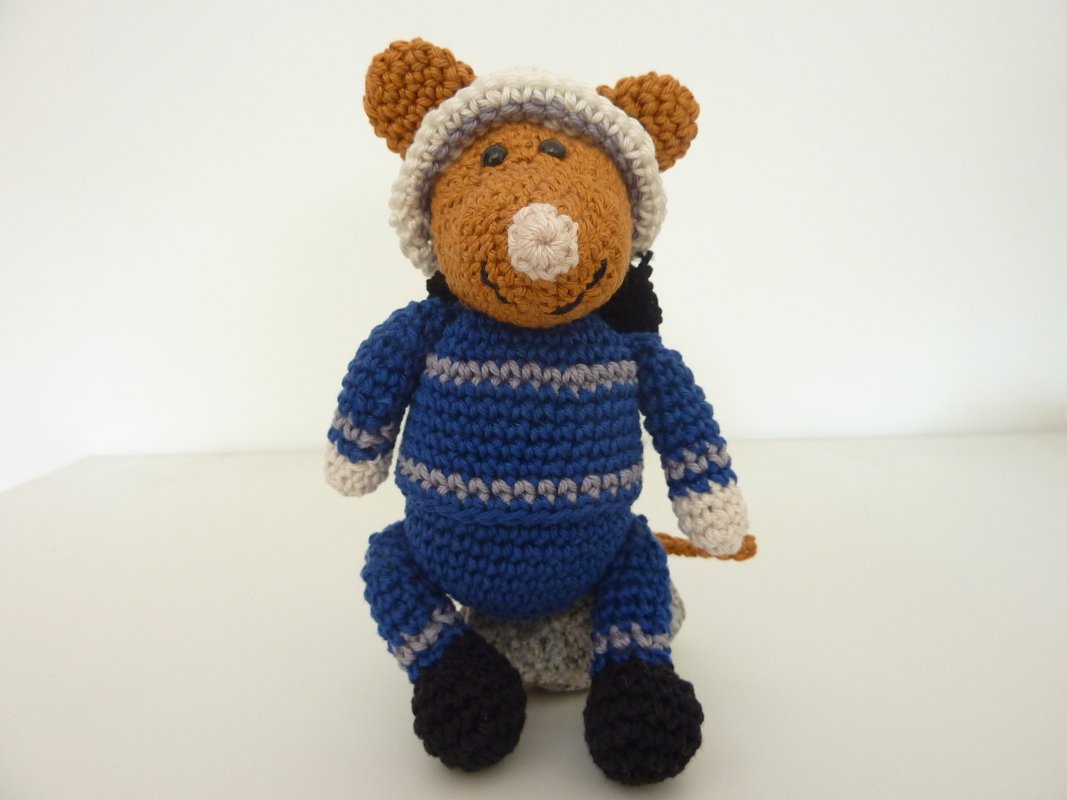 Gehäkelte braune Amigurumi‑Maus mit blau‑grauem Ringeloverall, beiger Mütze und kleinem Schwanz