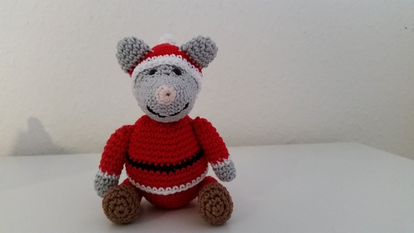 Gehäkelte Amigurumi-Maus in Rot und Grau mit Weihnachtsmütze auf weißem Hintergrund