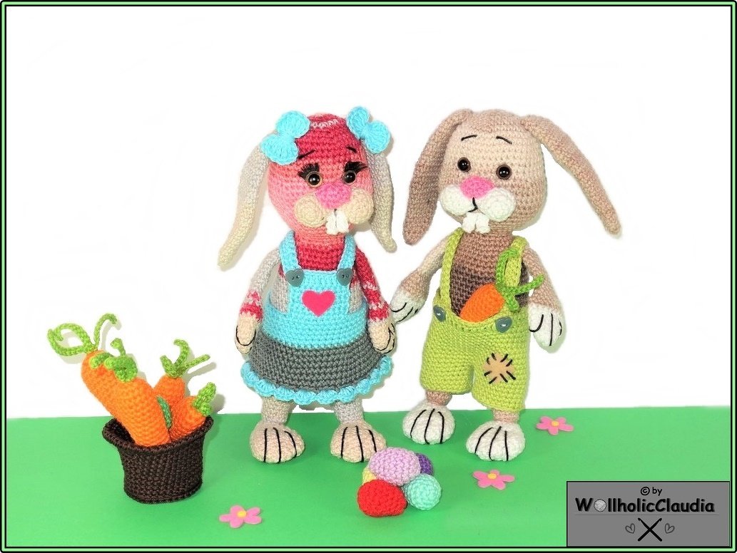 zwei bunte gehäkelte Osterhasen mit Kleid und Latzhose, Karotte in der Tasche und Korb mit gehäkelten Karotten