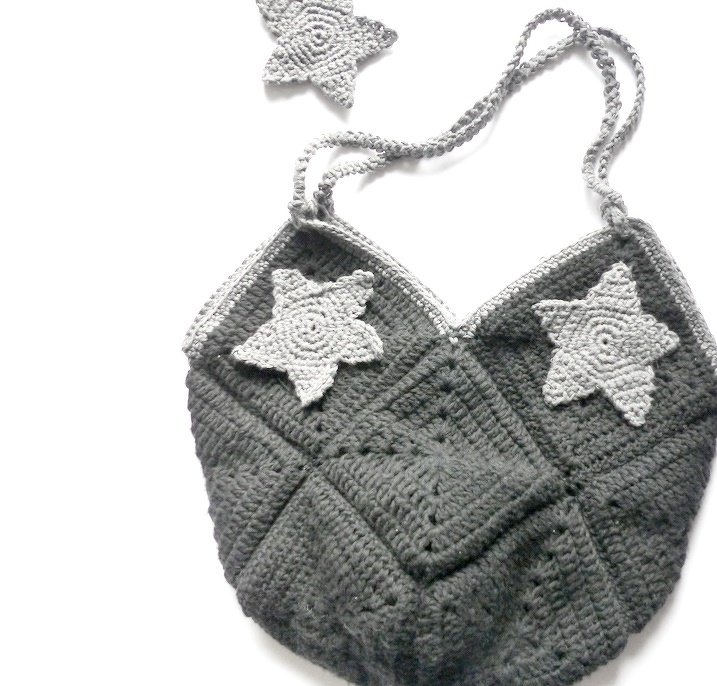 Gehäkelte Henkeltasche aus dunklen Granny Squares mit hellgrauen Stern-Applikationen und gedrehtem Träger