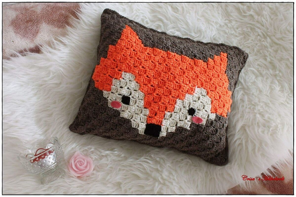 Pixelart-ähnliches gehäkeltes Kissen mit Fuchs-Motiv in Orange, Creme und Braun