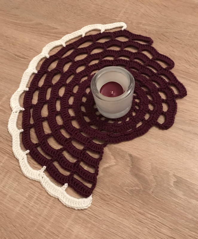 Gehäkeltes halbmondförmiges Deckchen in Bordeaux mit weißer Bogenkante und Glas-Teelicht