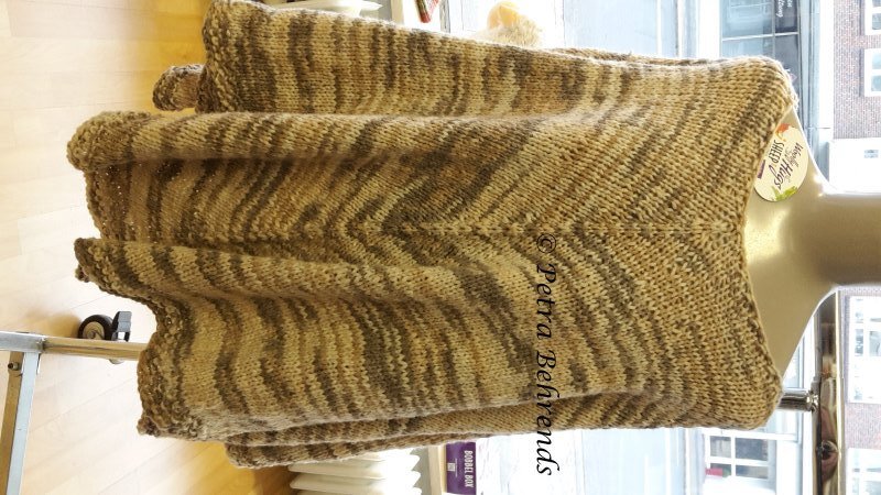 Gestrickter Poncho in Braun und Beige mit V-förmigem Streifenmuster auf Schaufensterpuppe