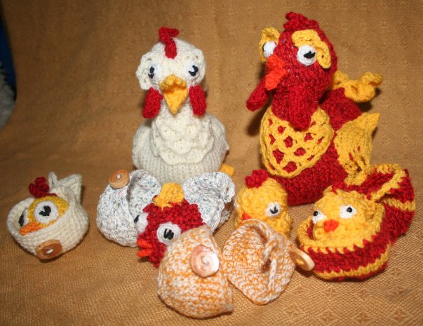 Gestrickte Amigurumi-Hühner und Eier in Creme, Gelb und Rot auf braunem Stoff