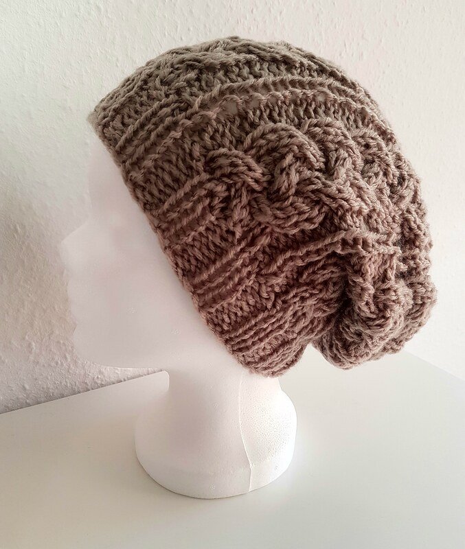 Gestrickte braune Beanie mit Zopfmuster auf weißem Modellkopf