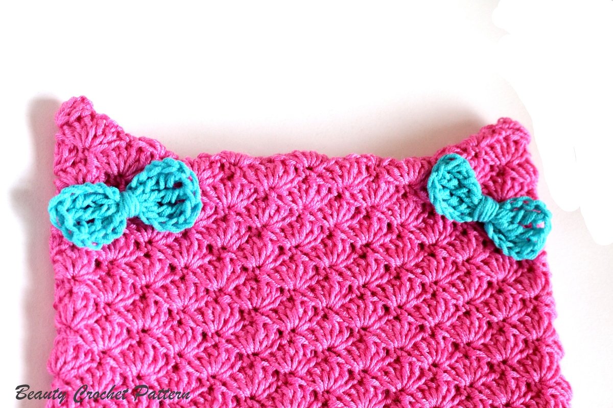 Pink crocheted earwarmer headband with shell stitch texture and two turquoise bows