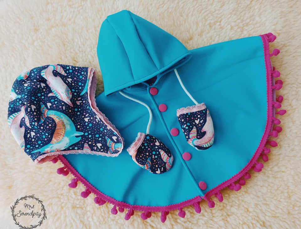 Runder türkiser Puppenponcho mit Kapuze, Stoffknöpfen und pinker Bommelkante, plus Mütze und Fäustlinge mit Meeresmotiv