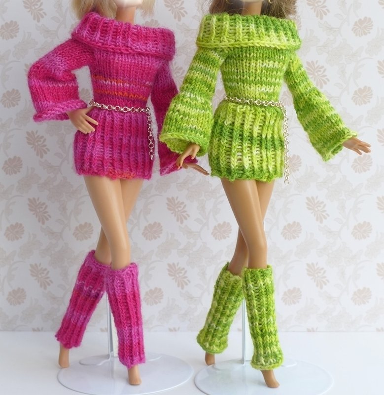 Zwei Puppen in gestrickten schulterfreien Minikleidern mit Glockenärmeln und passenden Beinstulpen, eine pink, eine grün.