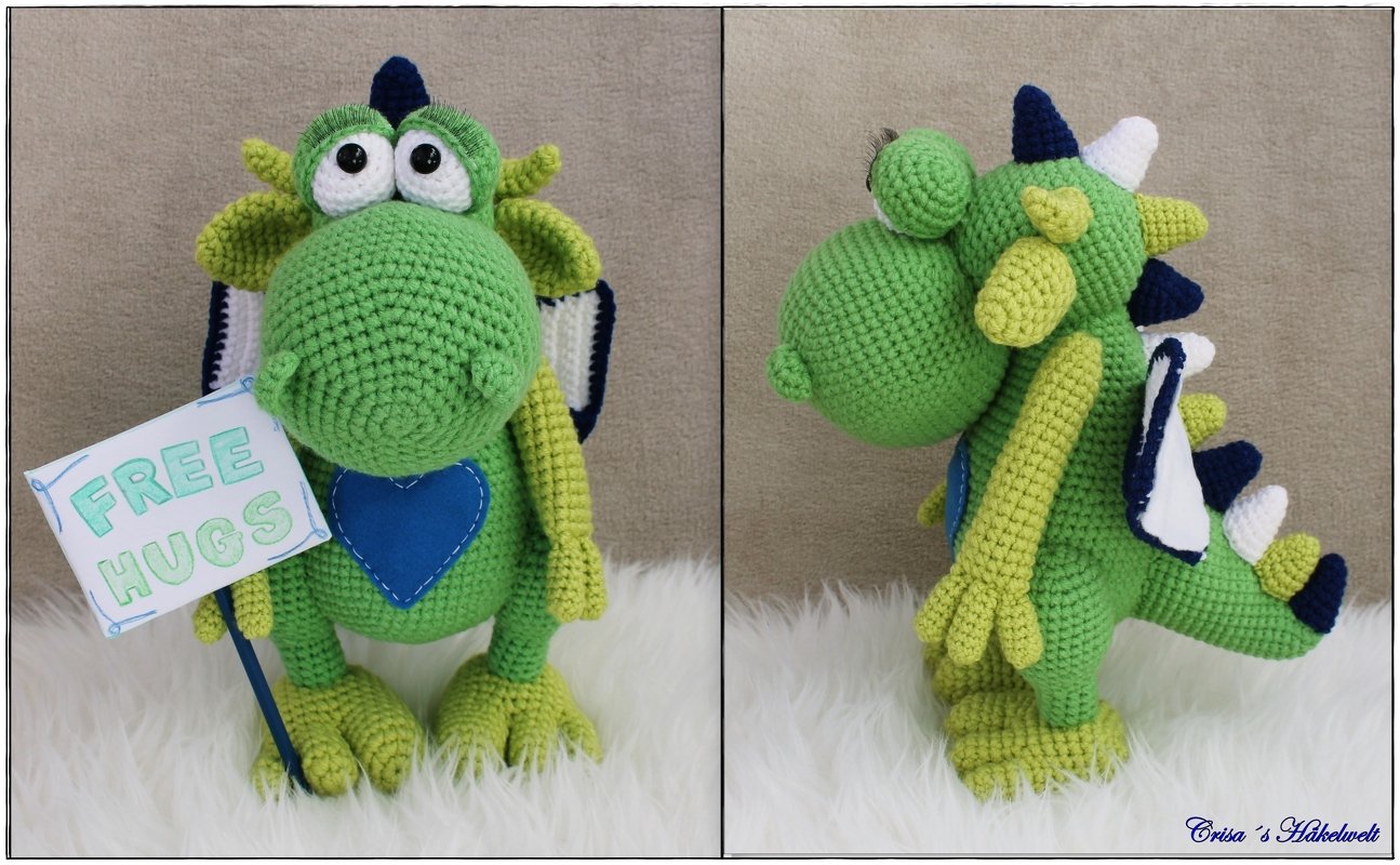 Frontalansicht eines gehäkelten grünen Amigurumi‑Drachen mit blauem Herz und 'FREE HUGS'-Schild