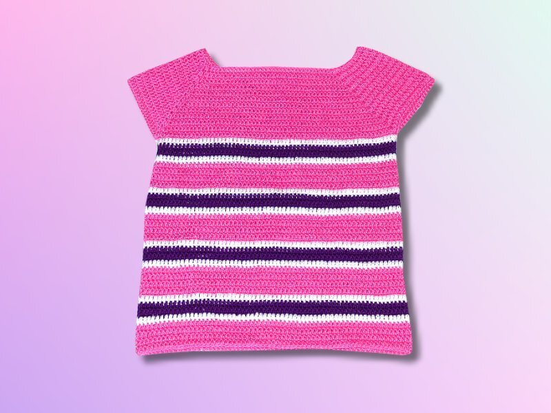 Gehäkelter Kinderpullover in Pink mit weißen und dunkelvioletten Streifen, kurze Ärmel, weiter Ausschnitt