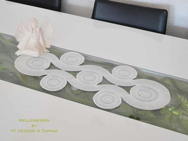 Gehäkelter weißer Tischläufer mit Wellen- und Kreisdesign auf modernem Esstisch mit Engelsfigur
