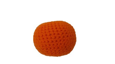 Gehäkelte orangefarbene Deko‑Frucht auf weißem Hintergrund.