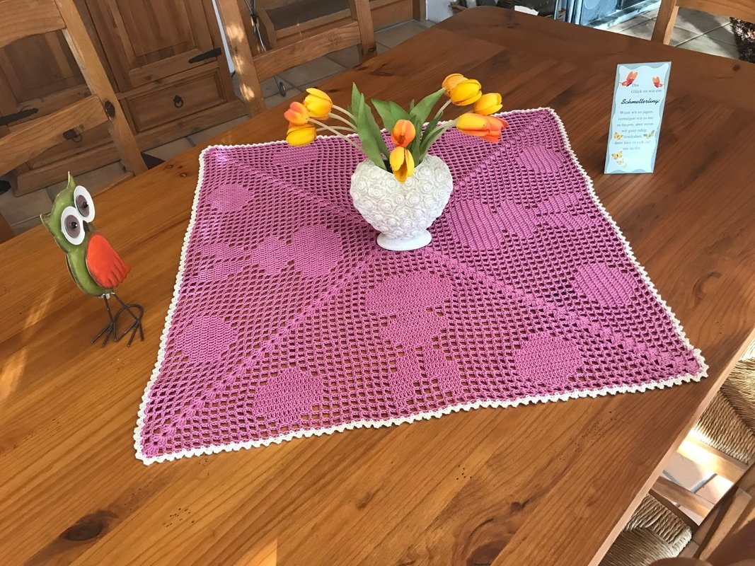 Quadratisches rosa gehäkeltes Deckchen mit weißer Muschelkante und Tulpenvase