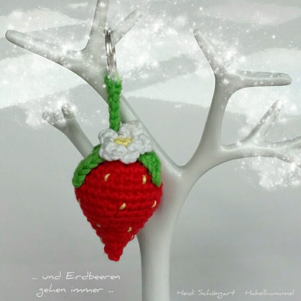 Gehäkelter roter Erdbeer‑Anhänger mit grünen Blättern, weißer Blüte und Metallring