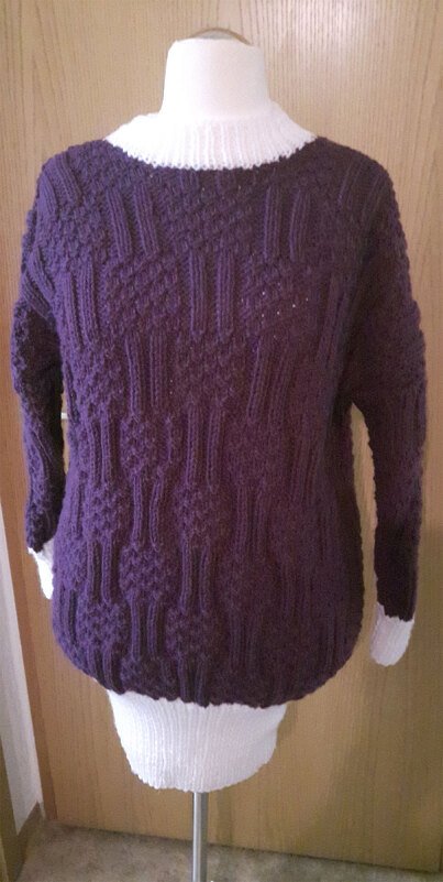 Dunkelvioletter gestrickter Damenpullover mit strukturiertem Muster und weißen Bündchen auf einer Schneiderpuppe