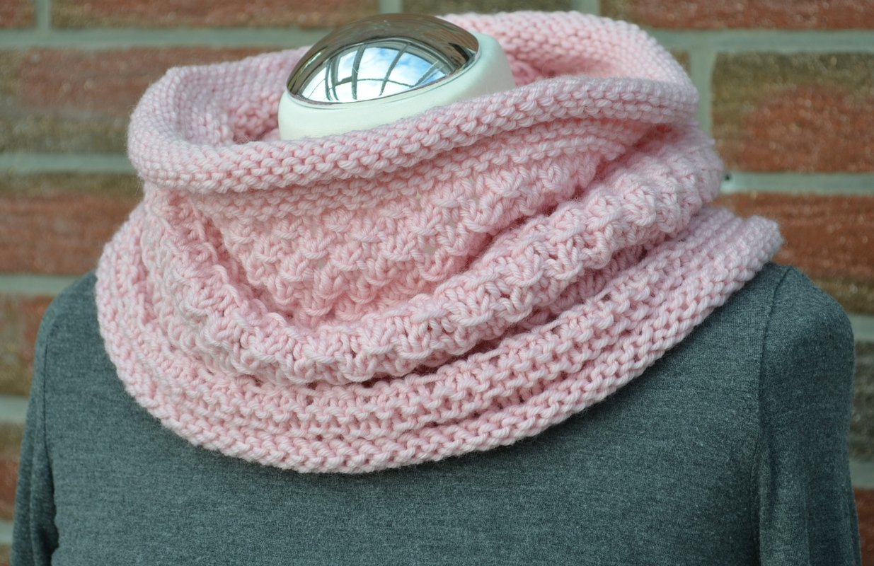 zartrosa gestrickter Loop, locker doppelt gelegt auf Schaufensterbüste vor Backsteinwand