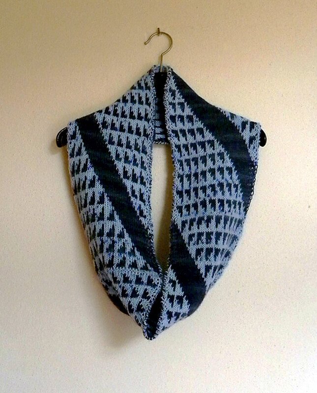 Gestrickter Loop-Schal in Hell- und Dunkelblau mit geometrischem Rautenmuster an einem Kleiderbügel
