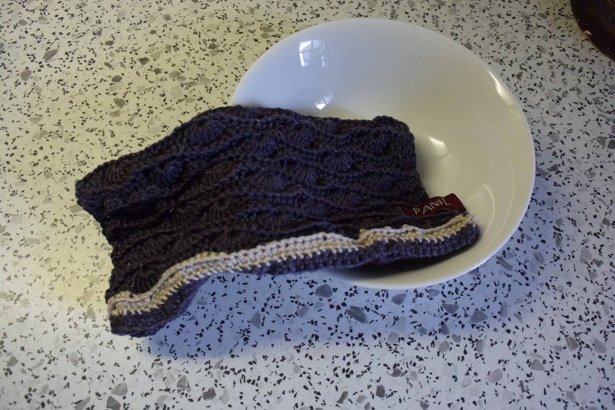 Gehäkelter Schalenüberzug mit Muschelmuster und hellem Rand in weißer Schale