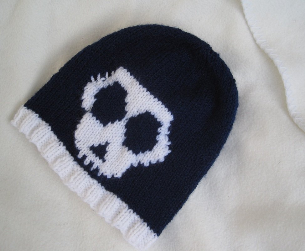 Dunkelblaue gestrickte Mütze mit weißem Totenkopf und geripptem weißen Bündchen