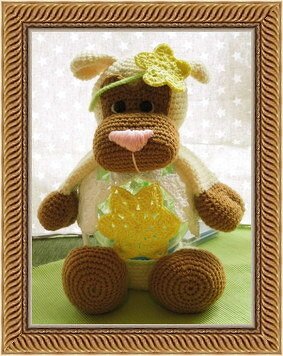 Gehäkeltes sitzendes Amigurumi in Braun und Creme mit rosa Schnauze und gelber Blüte