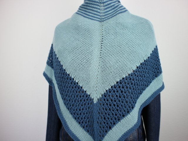 Rückansicht eines gestrickten Dreieckstuchs in hell- und dunkelblauen Tönen mit breitem Lochmusterstreifen und zentraler Naht.