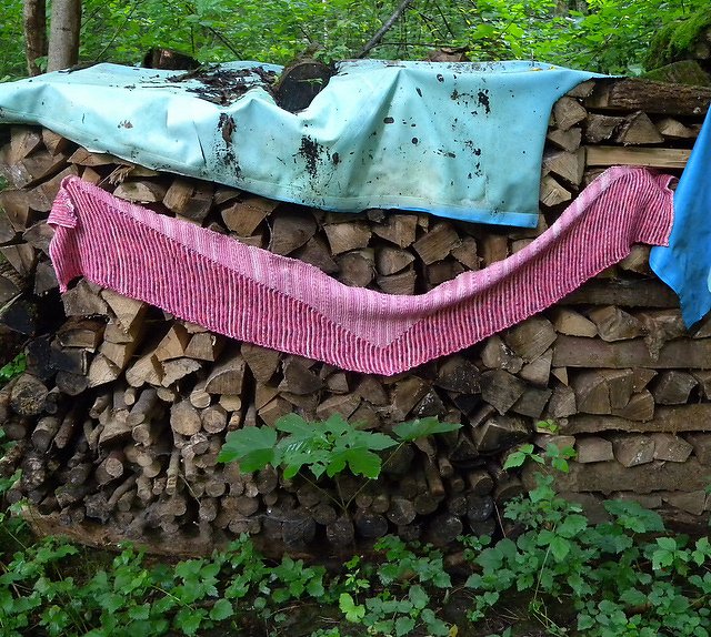 Detailaufnahme eines gerippten rosafarbenen Schals über einem Holzstapel
