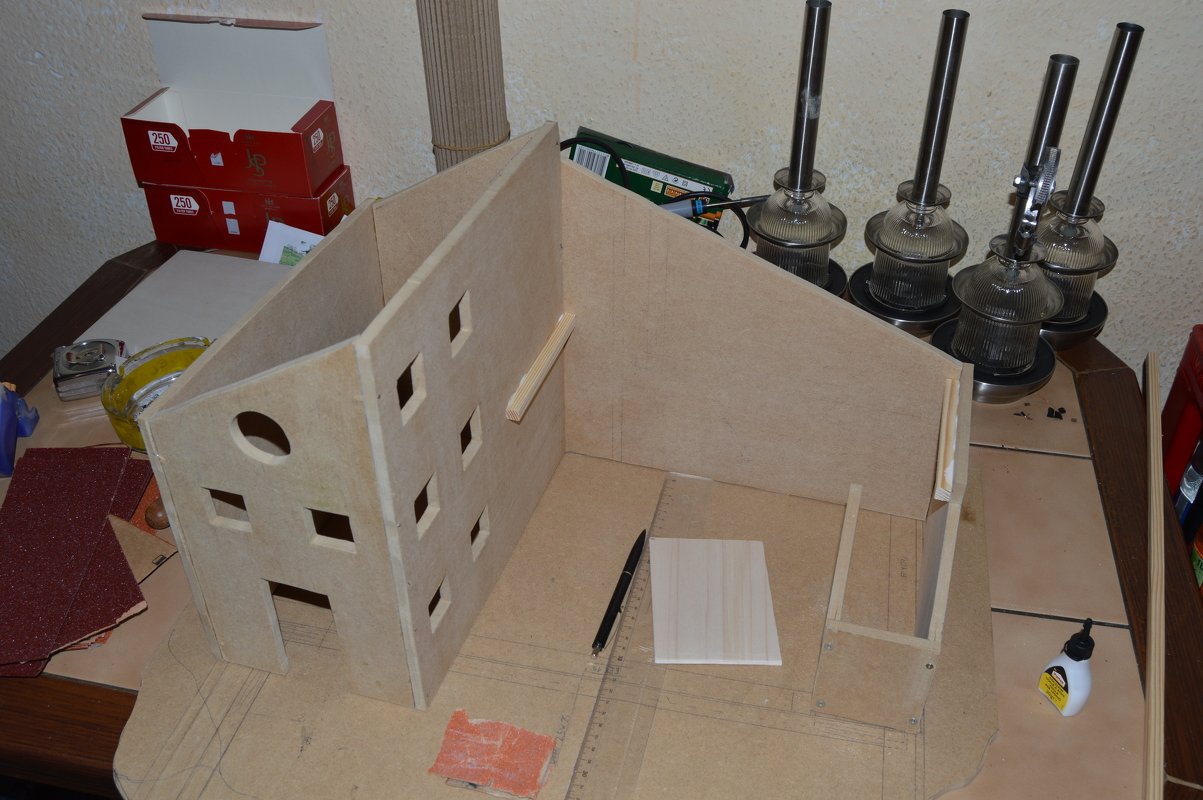 DIY-Holzspielzeughaus in Bauphase mit Werkzeugen und Zeichnungen