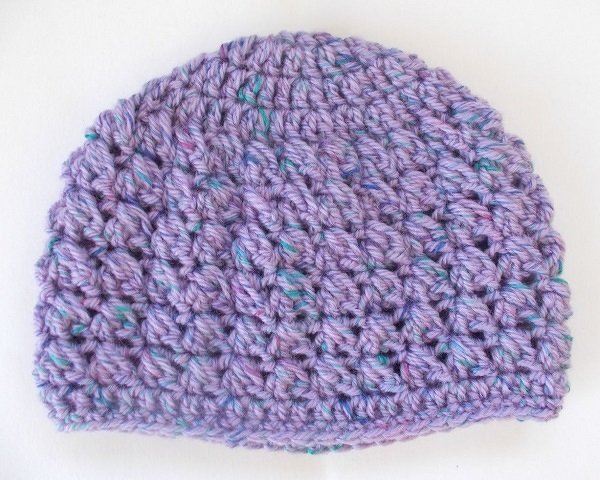 Lila gehäkelte Babymütze mit blauen und grünen Sprenkeln und Reliefstruktur