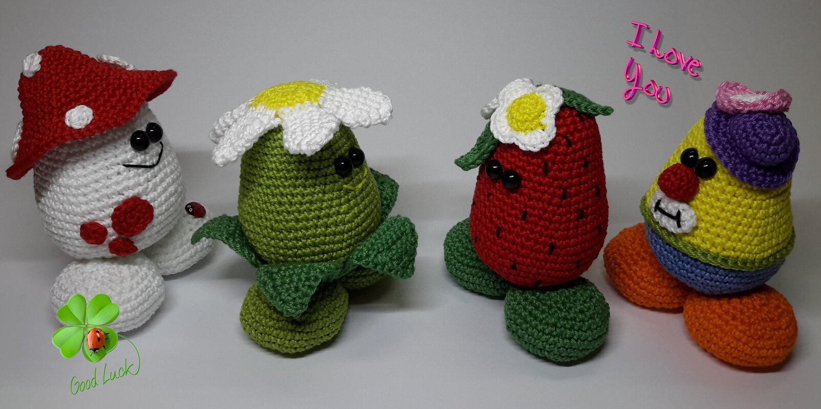 Vier gehäkelte Amigurumi-Glücksbringer: Pilz, Blume, Erdbeere und bunte Figur