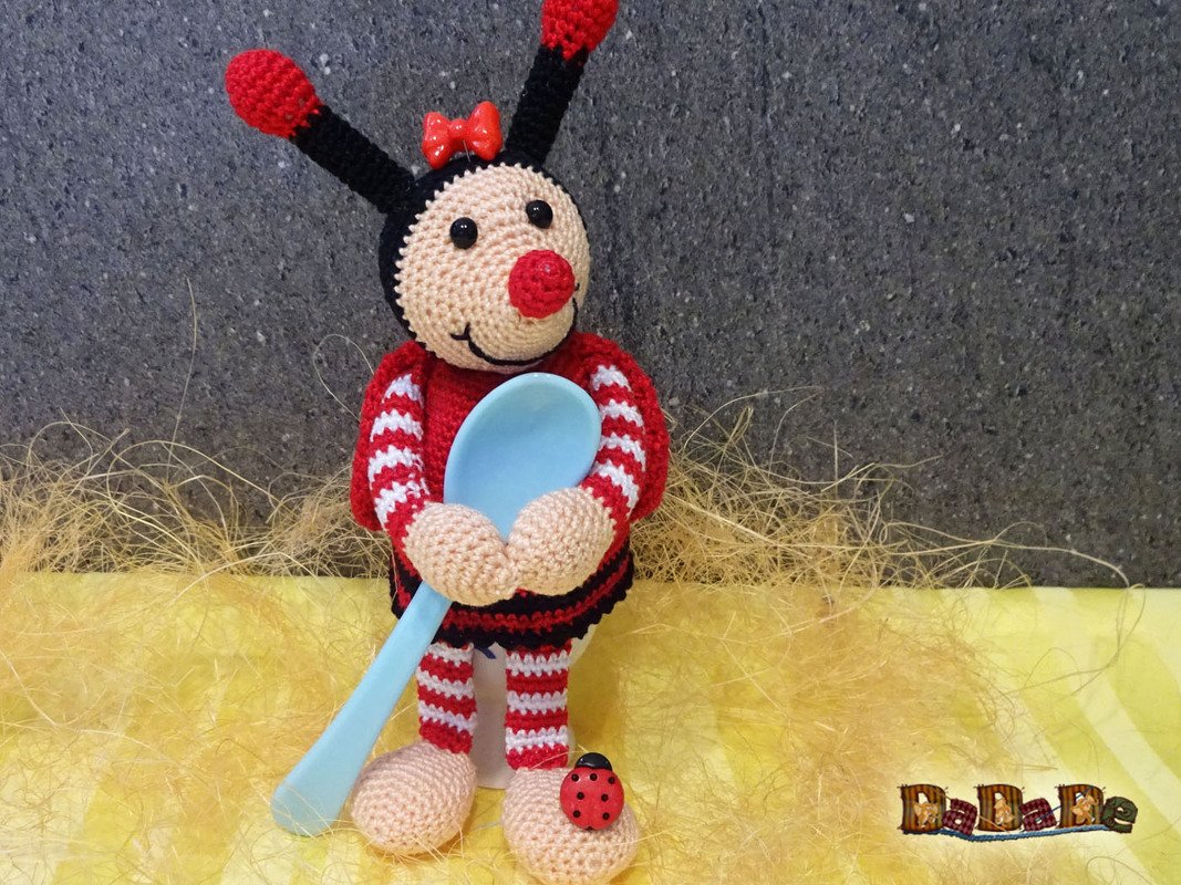 Gehäkelter Marienkäfer-Eierwärmer mit rotem Bogen, blauem Löffel und roten Antennen