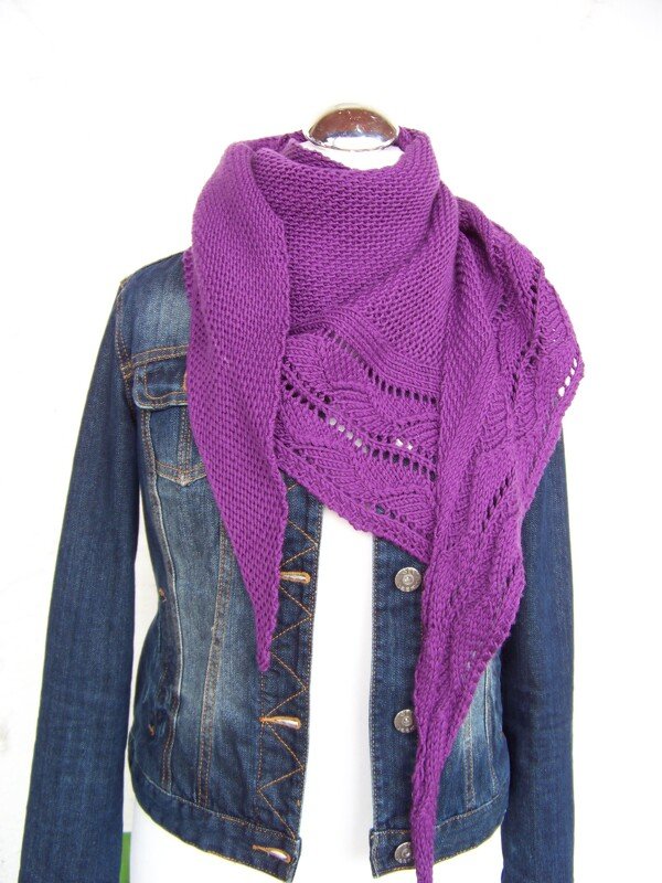 Lila gestricktes Dreieckstuch mit Lochmuster über einer Jeansjacke an einer Schneiderbüste.
