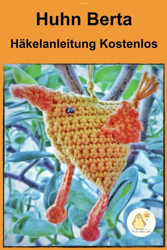 Gehäkeltes gelbes Huhn Berta mit orangefarbenen Flügeln und Beinen, hängend an einem Zweig