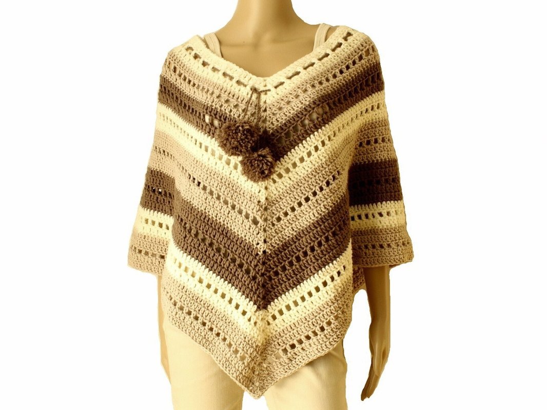 Mannequin trägt gehäkelten Poncho in Beige- und Brauntönen mit V‑Ausschnitt und Pompons