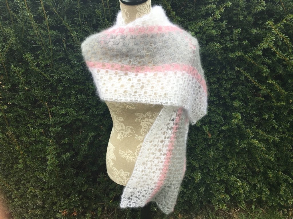 Gehäkelter weißer Schal mit rosa und grauen Streifen auf Schneiderpuppe