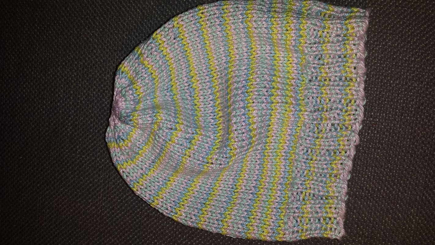 Gestrickte Babymütze in melierten Pastellfarben (Blau, Gelb, Rosa) auf dunklem Hintergrund